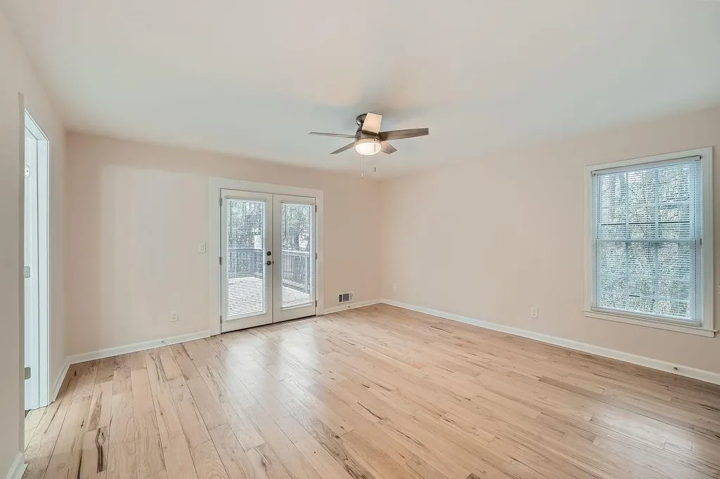 Empty room with a wealth of natural light, french doors, light wood-style flooring, and baseboards