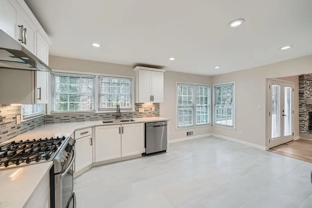 Kitchen featuring stainless steel appliances, light countertops, backsplash, white cabinetry, and a sink