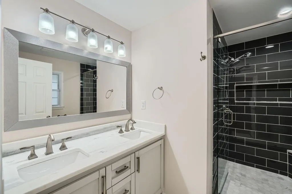 Bathroom with a tile shower, double vanity, and a sink