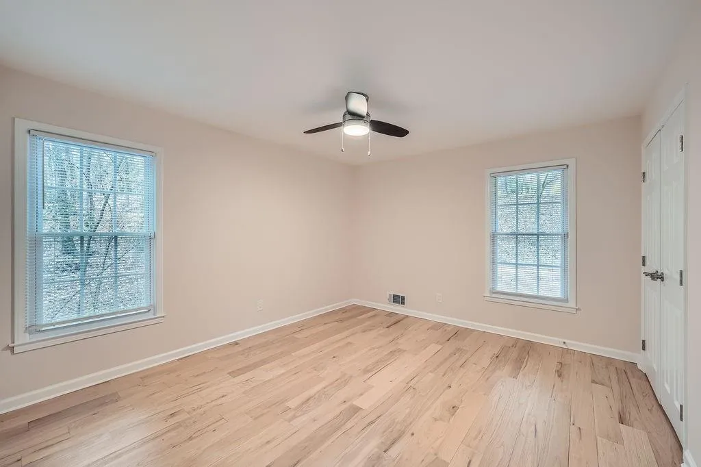 Empty room with visible vents, ceiling fan, light wood-style flooring, and baseboards