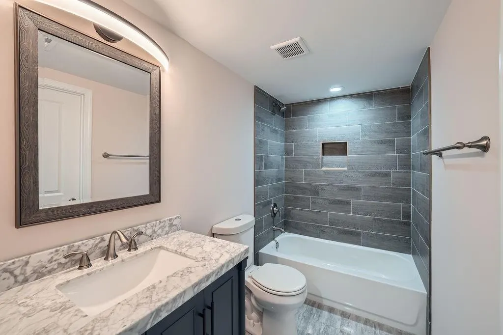 Bathroom with toilet, tub / shower combination, vanity, and visible vents