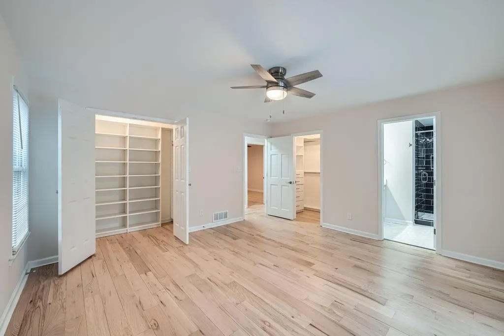Unfurnished bedroom featuring visible vents, baseboards, a closet, light wood-type flooring, and a walk in closet
