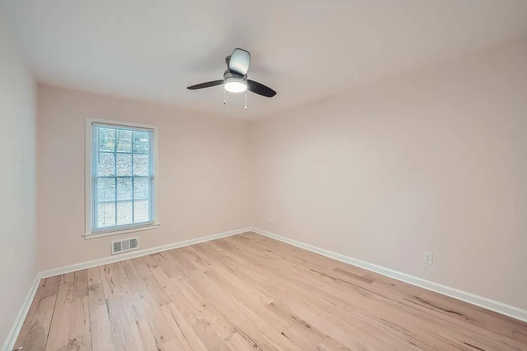 Unfurnished room featuring light wood-style floors, visible vents, baseboards, and a ceiling fan