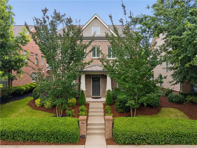 Brick facade residence featuring a covered entry, shuttered windows, and a peaked gable roofline