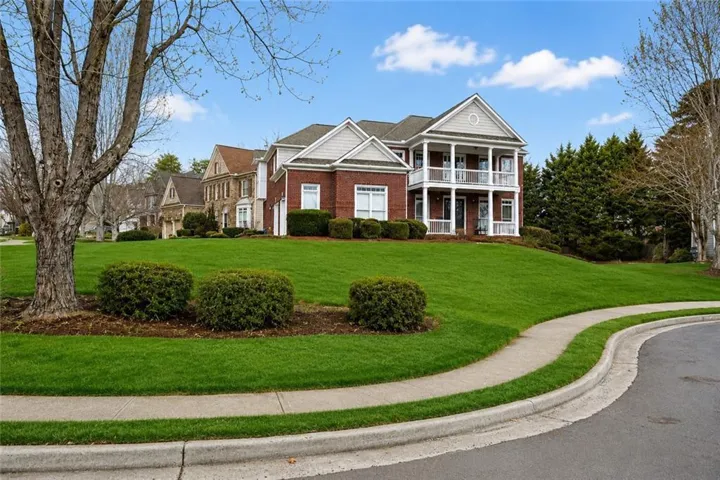 Two-story brick exterior with white trim, featuring a double-decker porch with white railings and columns