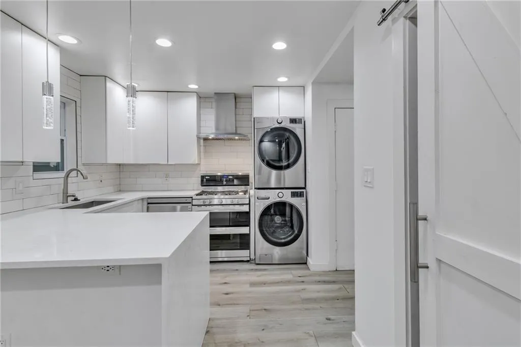 Laundry area featuring light wood finished floors, recessed lighting, and stacked washer / drying machine
