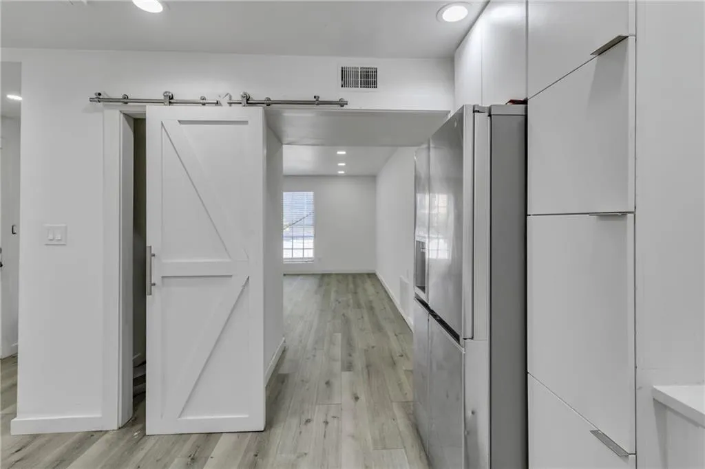 Hallway with light wood-style flooring, a barn door, and recessed lighting