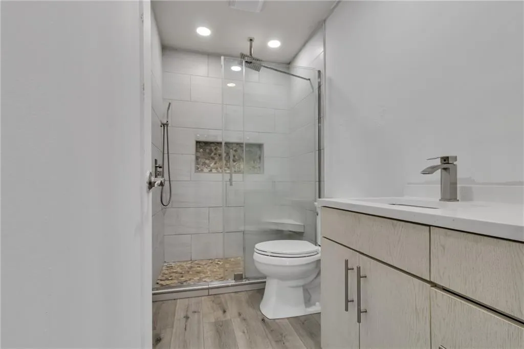 Full bath with vanity, a shower stall, light wood-style flooring, and recessed lighting