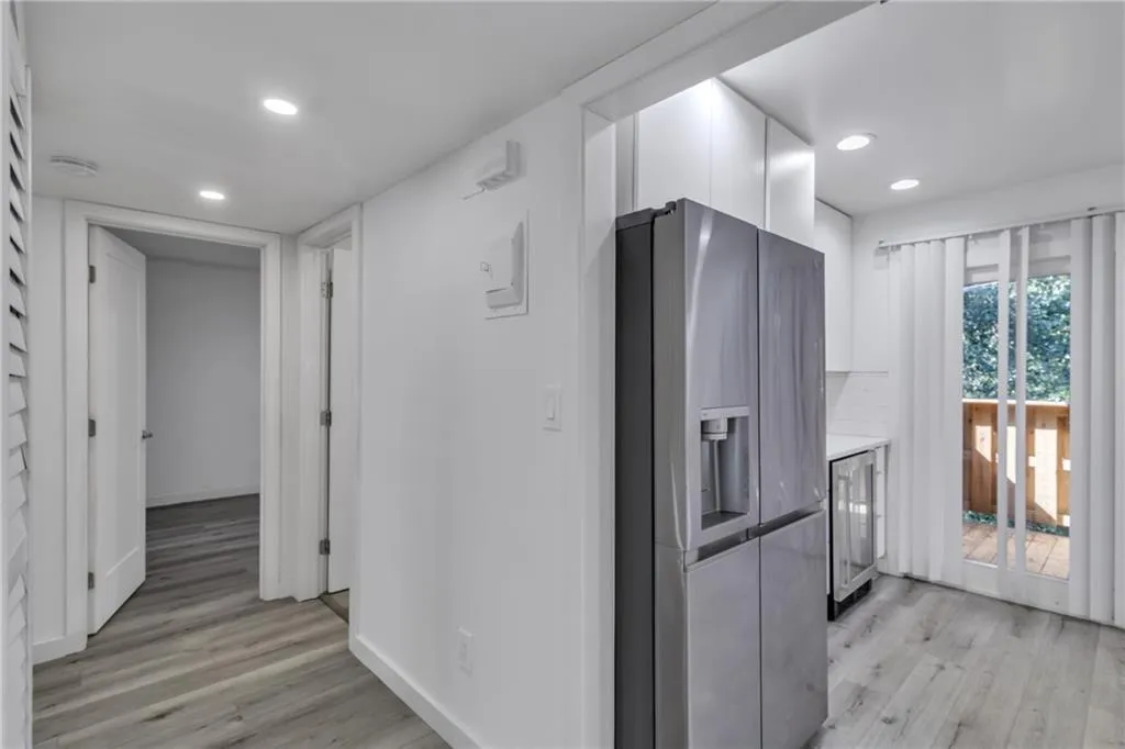Kitchen with stainless steel fridge, white cabinets, light wood-style flooring, wine cooler, and modern cabinets