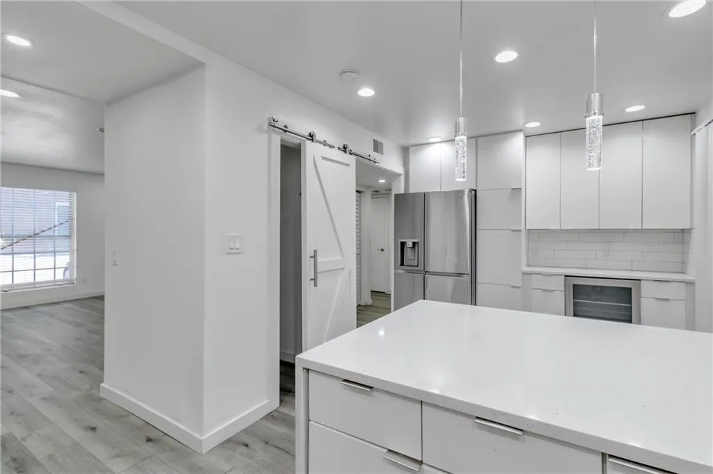 Kitchen with modern cabinets, white cabinetry, a barn door, and light stone countertops