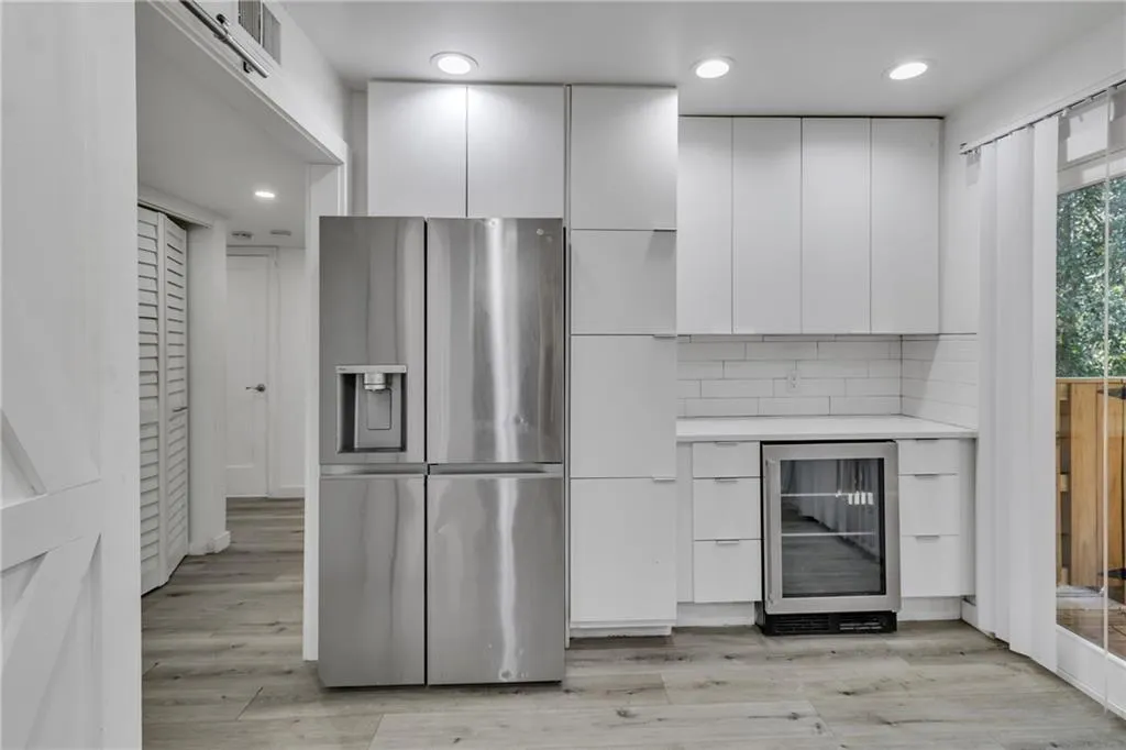Kitchen with stainless steel fridge, modern cabinets, beverage cooler, white cabinetry, and recessed lighting