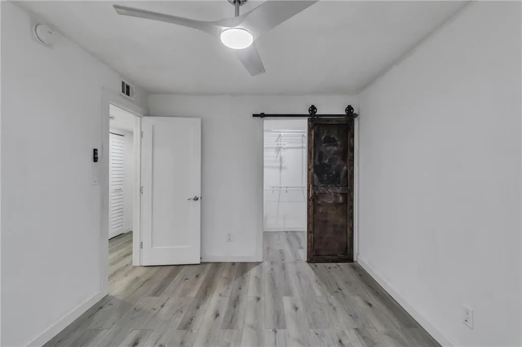 Unfurnished bedroom featuring a spacious closet, light wood-style floors, and ceiling fan