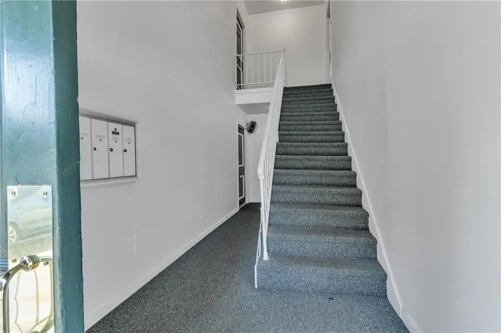 Stairway with mail area, carpet flooring, and a high ceiling