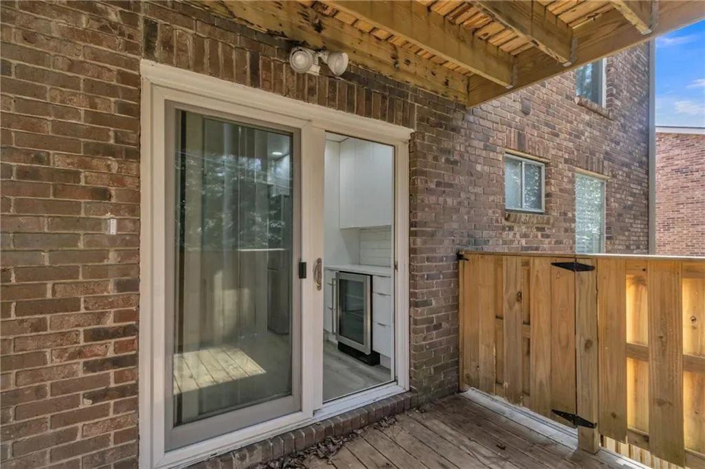 Property entrance featuring brick siding, wine cooler, and a wooden deck