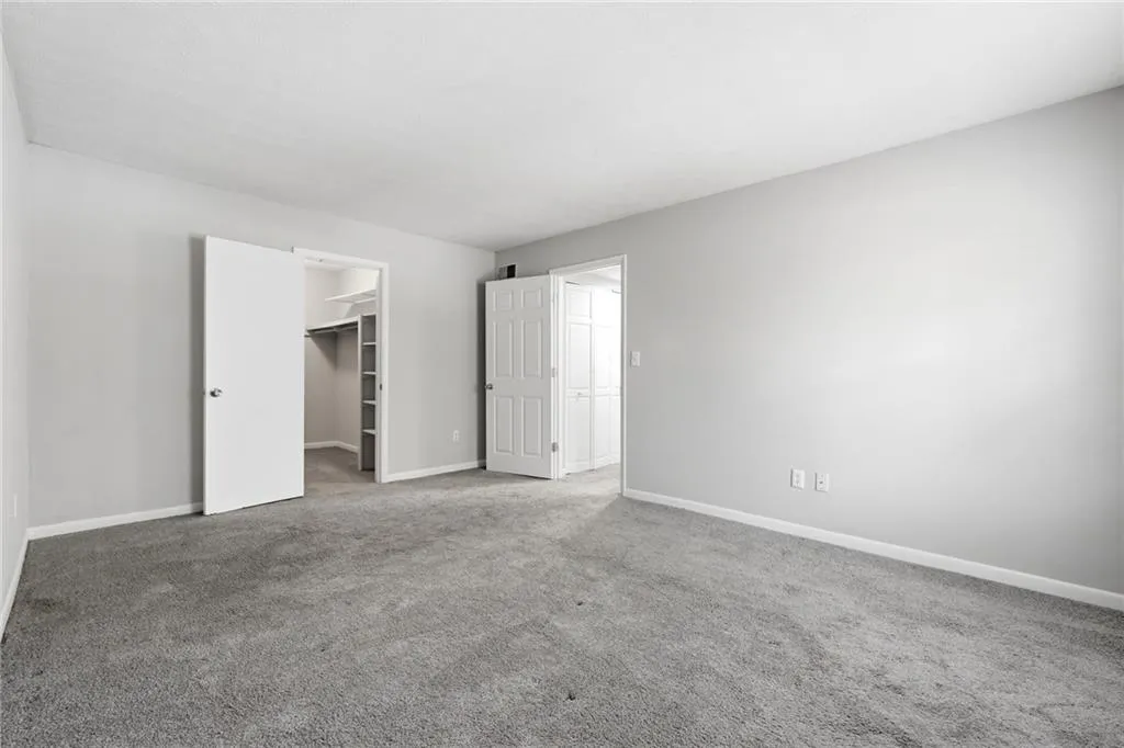 Unfurnished bedroom featuring a walk in closet and carpet