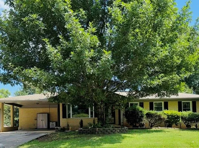 Brick exterior with a prominent mature tree and a manicured lawn