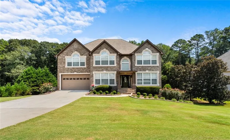 View of front of home with a front yard, driveway, an attached garage, and brick siding