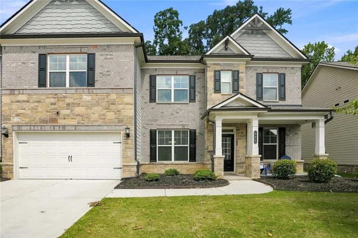 Stone and brick facade with shake siding accents, covered front porch, attached two-car garage, and manicured landscaping