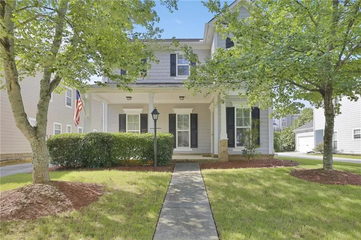 Two-story property featuring light-colored siding, contrasting dark shutters, and a covered front porch with white columns