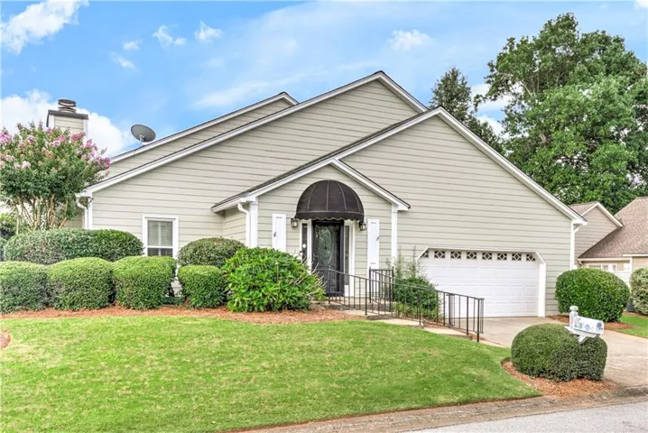Exterior featuring light-colored siding and a black front door awning