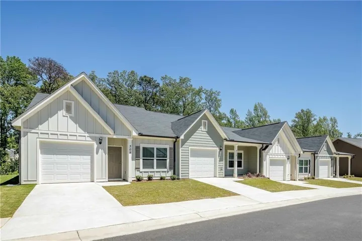 View of front of property featuring board and batten siding, driveway, and a garage