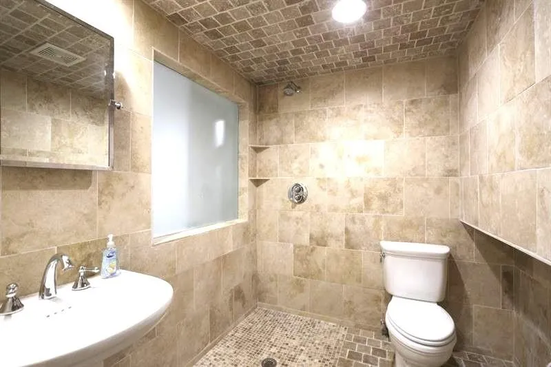 Bathroom with tile walls, sink, toilet, and tiled shower