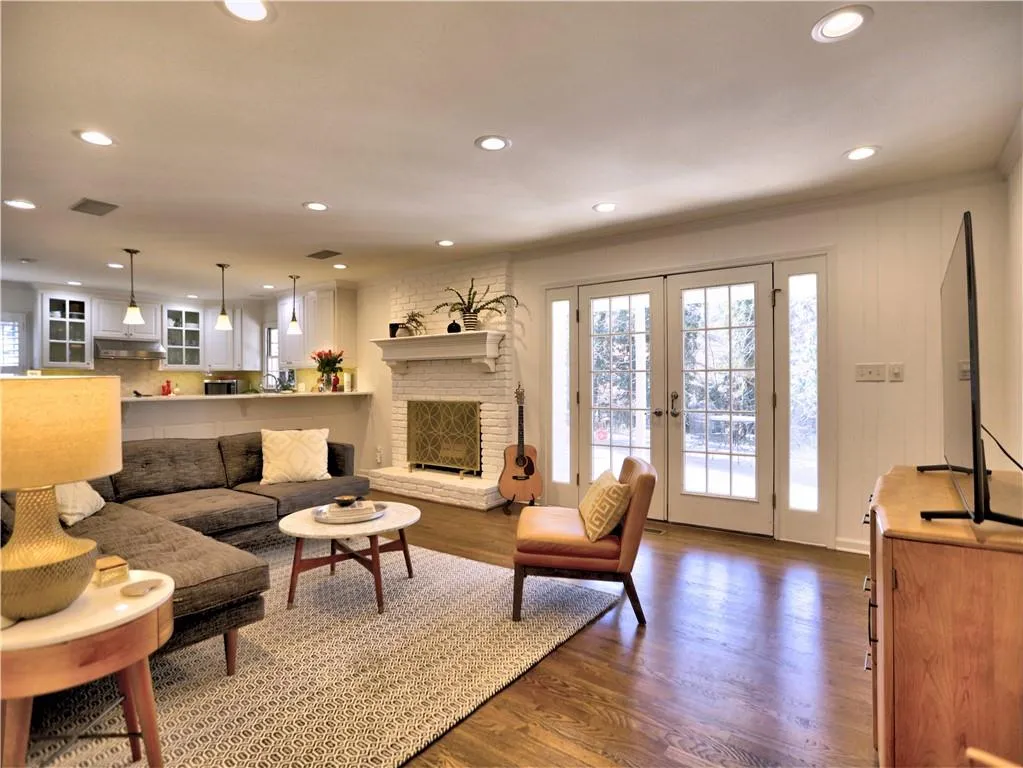 Living room with a brick fireplace, ornamental molding, dark hardwood / wood-style floors, and french doors