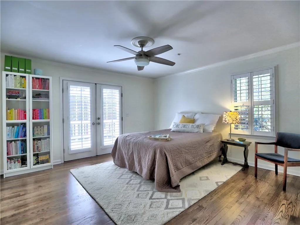 Bedroom featuring wood-type flooring, ornamental molding, access to exterior, ceiling fan, and french doors