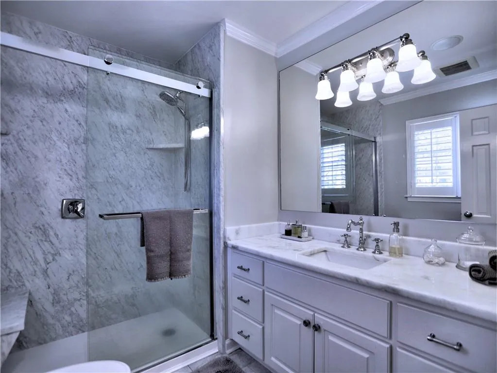 Bathroom featuring crown molding, vanity, and a shower with shower door