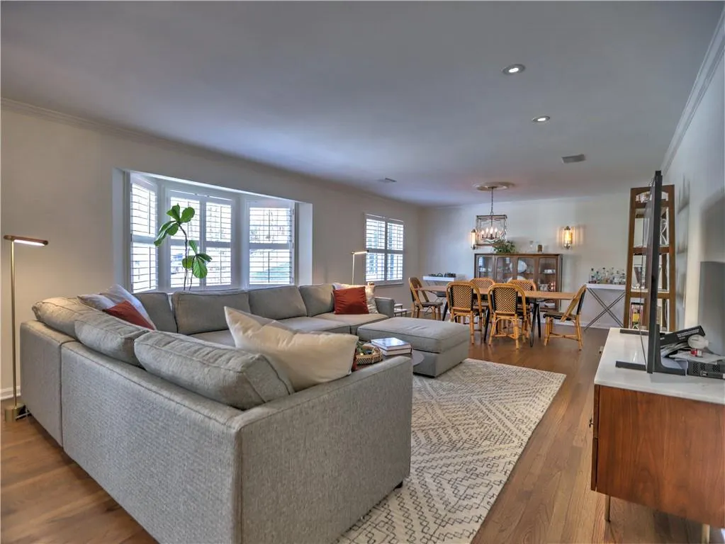 Living room featuring an inviting chandelier, ornamental molding, and hardwood / wood-style floors