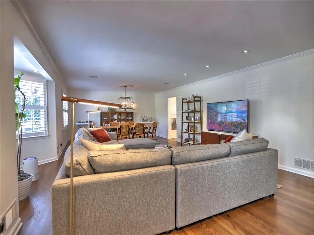 Living room featuring crown molding, dark hardwood / wood-style flooring, and an inviting chandelier