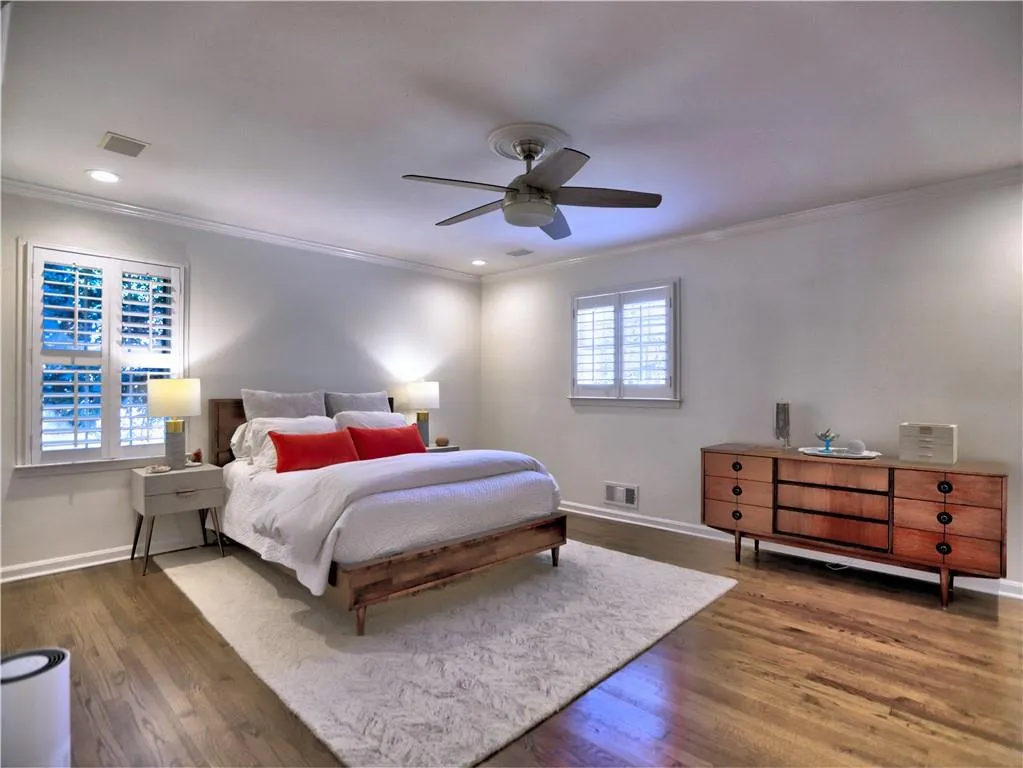 Bedroom with crown molding, ceiling fan, and dark hardwood / wood-style flooring