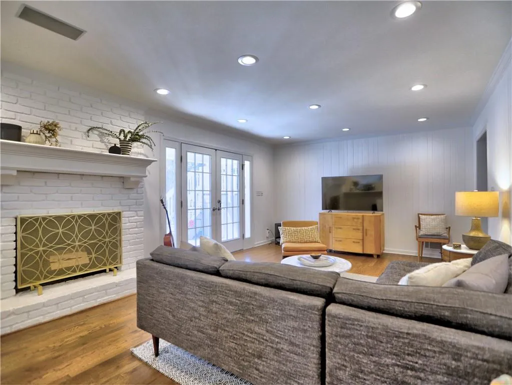 Living room with ornamental molding, a brick fireplace, hardwood / wood-style floors, and french doors