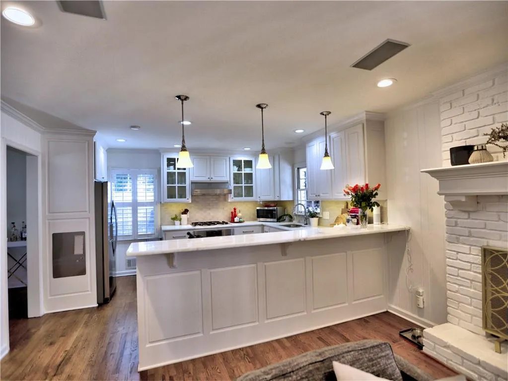 Kitchen featuring white cabinetry, decorative light fixtures, a fireplace, and kitchen peninsula