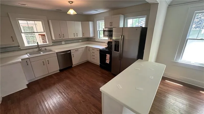 Kitchen featuring stainless steel appliances, dark wood finished floors, white cabinetry, and light countertops