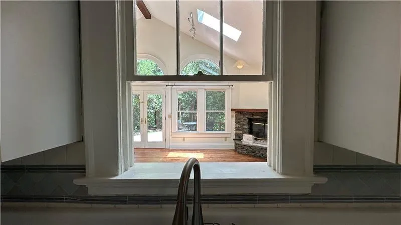 Detailed view of a stone fireplace, a skylight, and wood finished floors