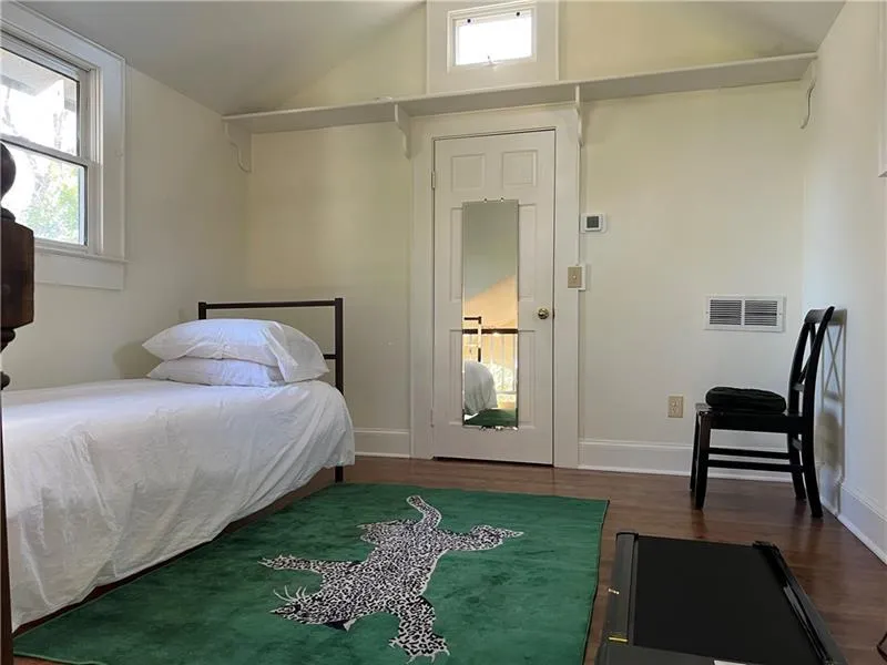 Bedroom featuring wood finished floors, multiple windows, and high vaulted ceiling