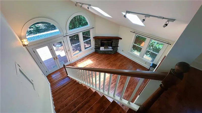 Staircase featuring rail lighting, hardwood / wood-style floors, a skylight, lofted ceiling, and healthy amount of natural light