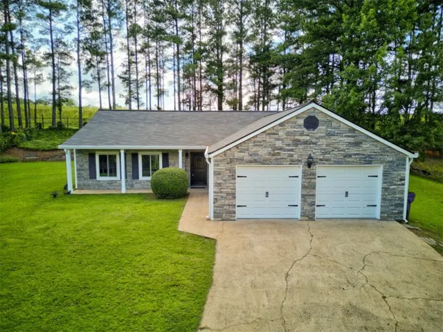 Stone veneer exterior with a two-car garage, covered entry, and a paved driveway