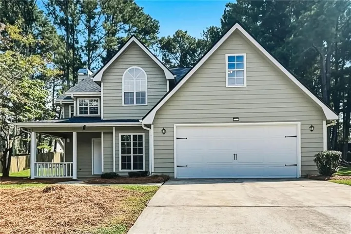 Gabled exterior with horizontal siding, covered porch, arched window accent, and an attached two-car garage