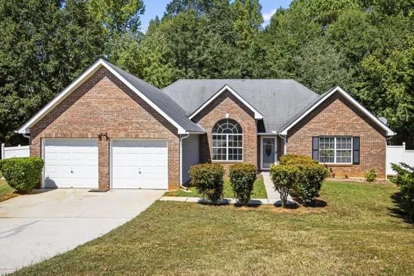 Brick facade residence featuring a two-car garage, an arched window, and a front entry with a transom