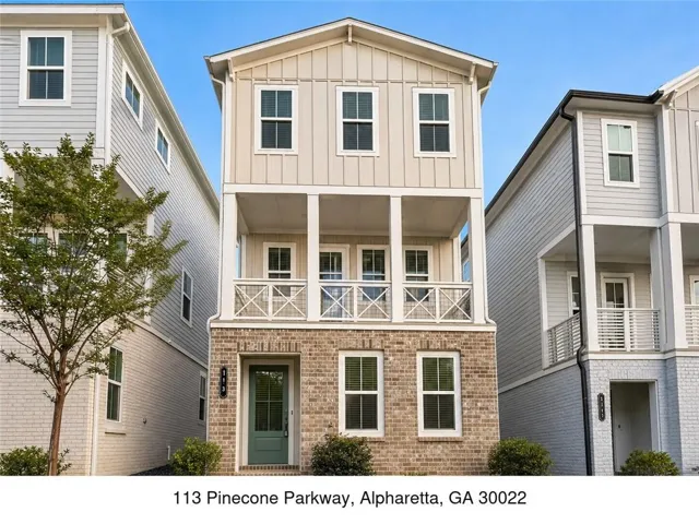 Charming three-story residence featuring a brick and board-and-batten exterior with a covered front porch, multi-pane windows, and a peaked roofline