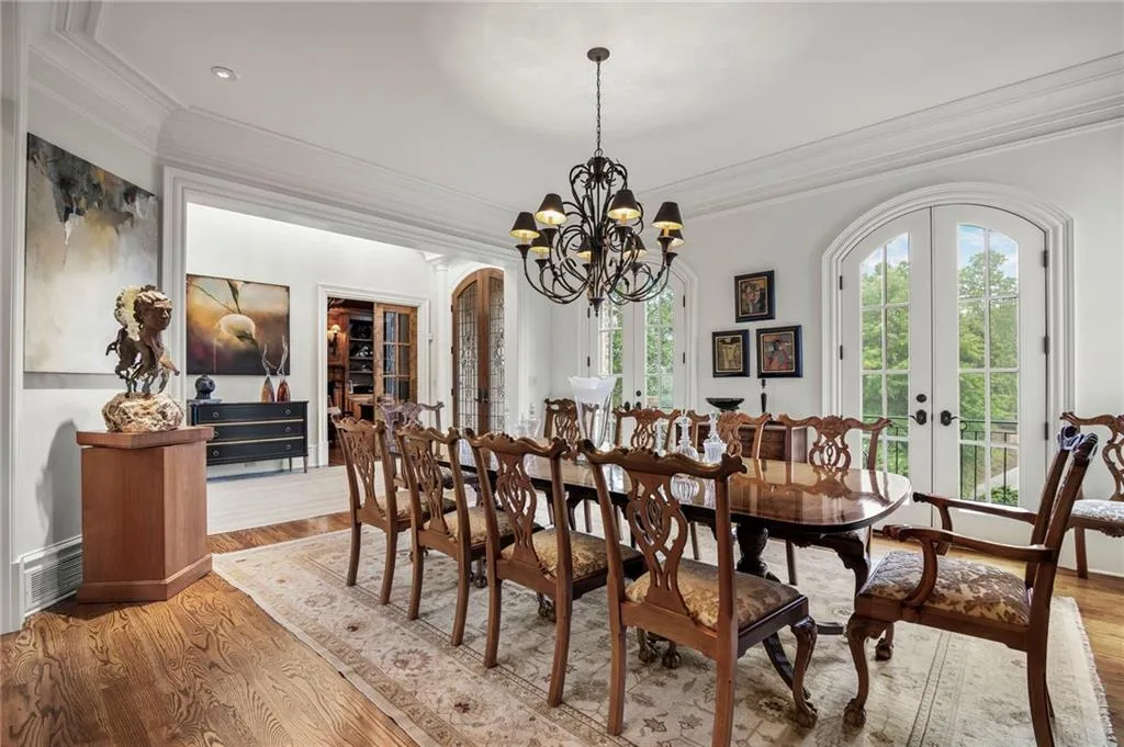 Hardwood flooring, arched French doors, ornate chandelier, crown molding, and recessed lighting