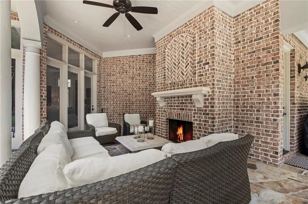 Covered patio featuring a brick fireplace with a decorative herringbone pattern, a classic white mantel, and flagstone flooring