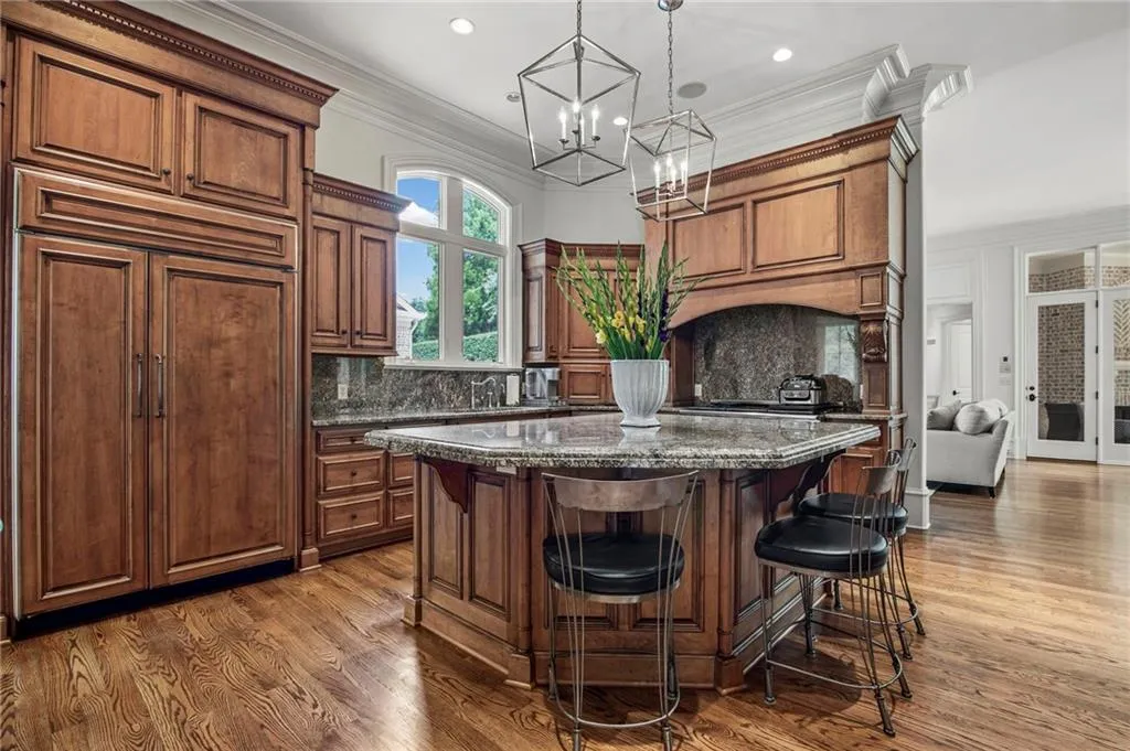 Kitchen featuring wood cabinetry, integrated refrigerator, granite countertops, and wood-finish flooring