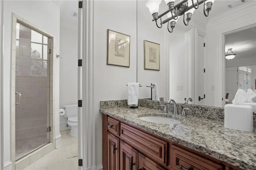 Terrace Level Bathroom - Granite countertop vanity with dual-handle faucet, full-width mirror, and glass-enclosed shower with tile surround