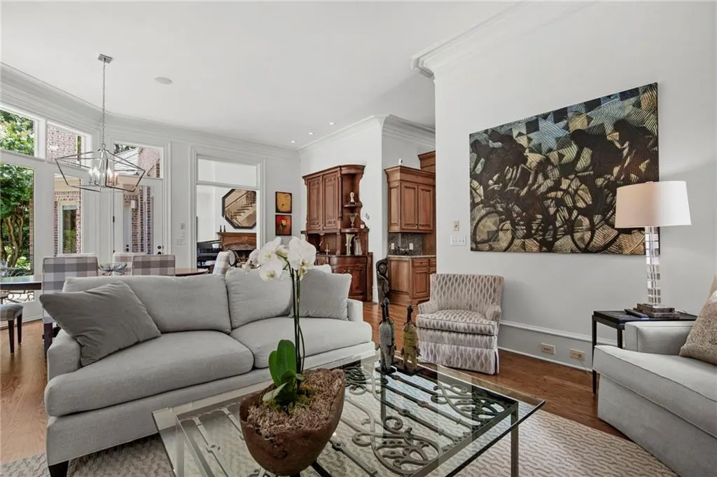 Hardwood flooring, crown molding, built-in cabinetry, geometric pendant lighting, and abundant windows