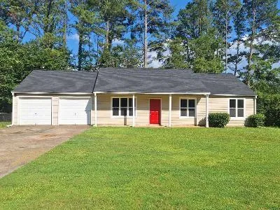 Single-story residence featuring a dual-bay garage with white doors, a red entry door, and a covered porch
