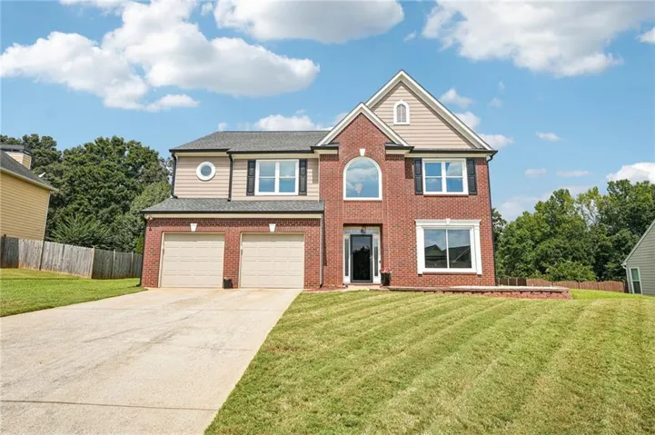 Brick and siding exterior with a two-car garage, arched entry window, and decorative shutters