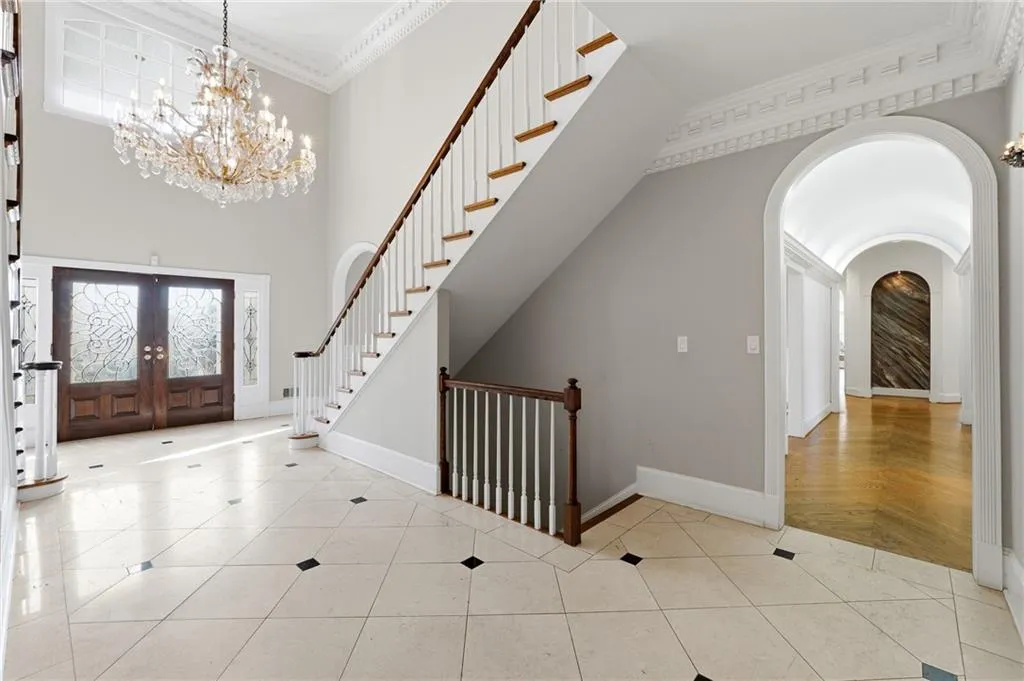 Entryway with ornamental molding, a high ceiling, suspended lighting, french doors, and light tile patterned flooring